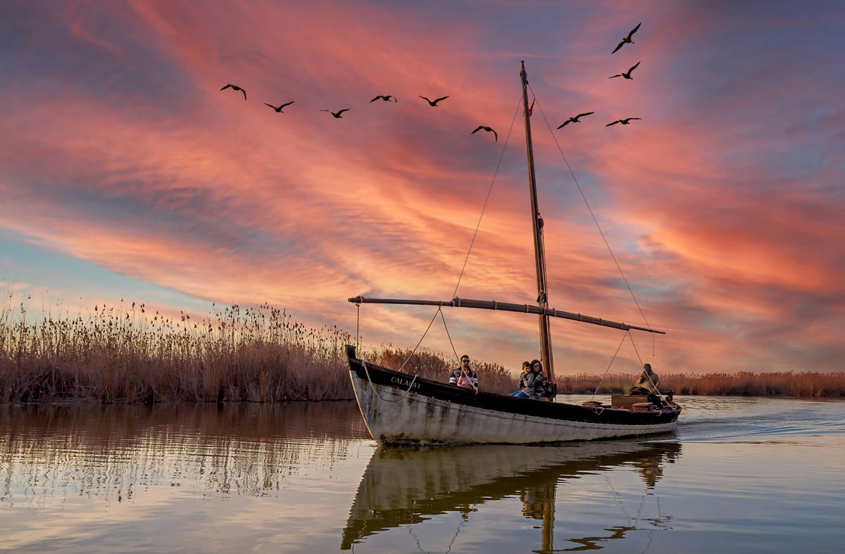 Canal cu stuf și apă liniștită în Delta Dunării, văzut într-o lumină caldă